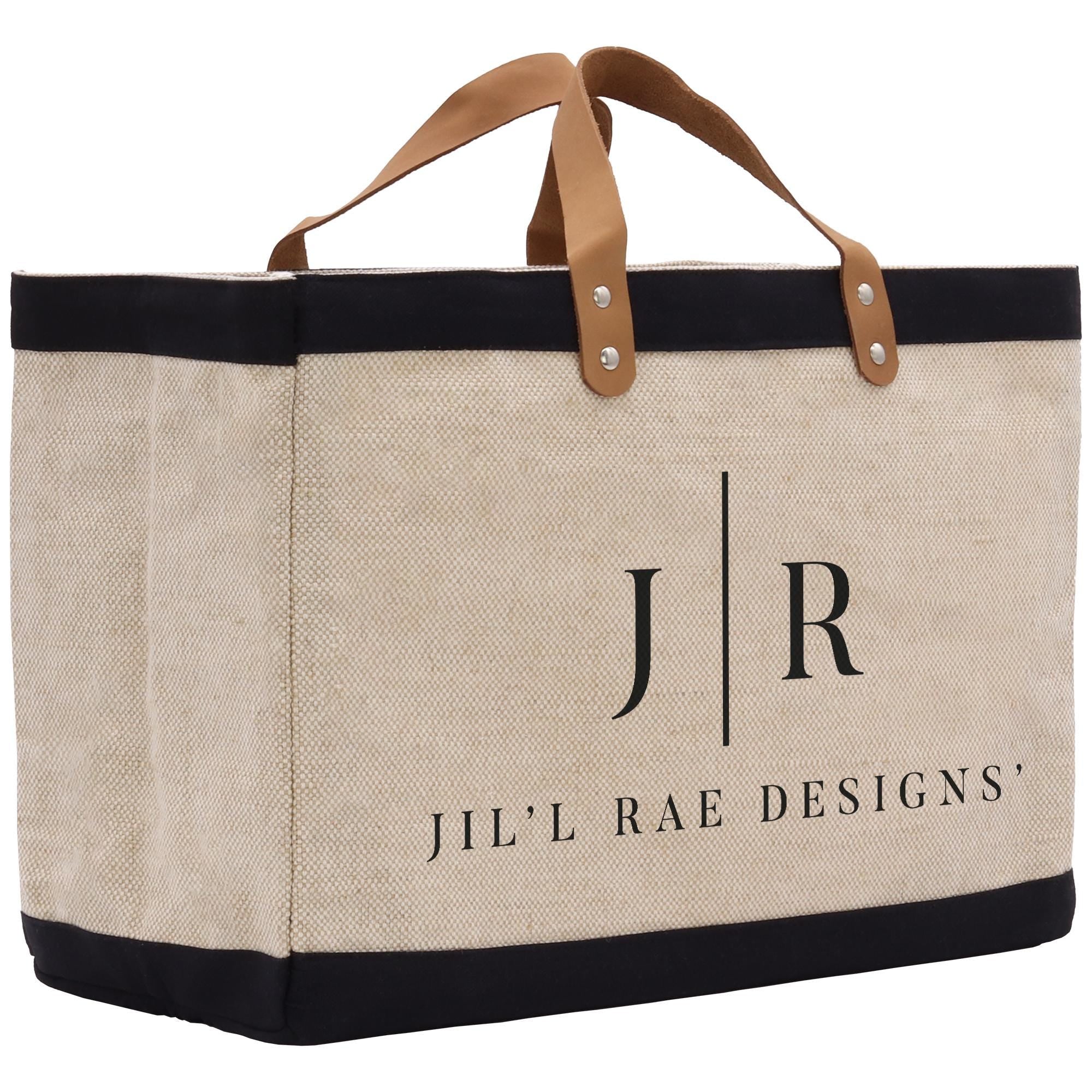A beige canvas tote bag with black trim and leather handles, featuring the text &quot;Jil&#39;l Rae Designs&quot; printed on it.