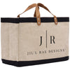 A beige canvas tote bag with black trim and leather handles, featuring the text "Jil'l Rae Designs" printed on it.