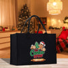 A black tote bag with a Christmas-themed design, featuring a gingerbread man and other holiday-related elements, placed on a wooden surface.