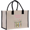 A beige canvas tote bag with black handles and straps, featuring a printed design of a bookcase with colorful books and flowers.