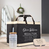 a black tote bag with white text and logos, a clear glass jar with a straw, and a small metal tin with a lid, all placed on a wooden surface.