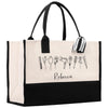 A large tote bag with a black and white design featuring various hair styling tools such as a hair dryer, curling iron, and scissors. The bag has a name tag attached to it, and the name 'Recca' is written below the design.