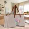 A beige tote bag with a colorful, personalized design featuring the name "Rebecca" and the phrase "A tiny human's bigger".