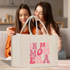 two women sitting on a couch looking at a bag