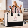 A woman is sitting on a couch in a living room, holding a black and white tote bag with a Paris-themed design.