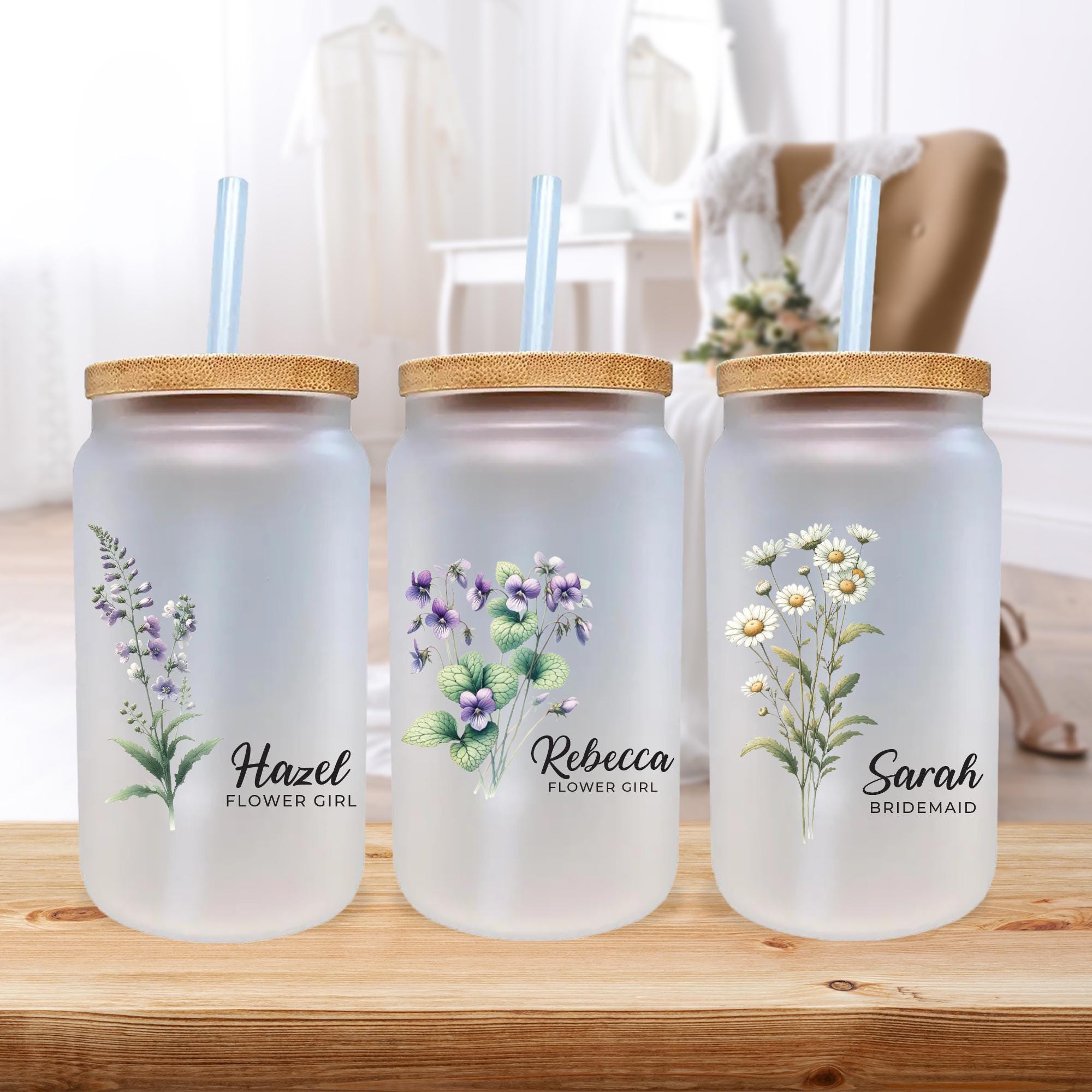 three glass jars with flowers on them sitting on a table