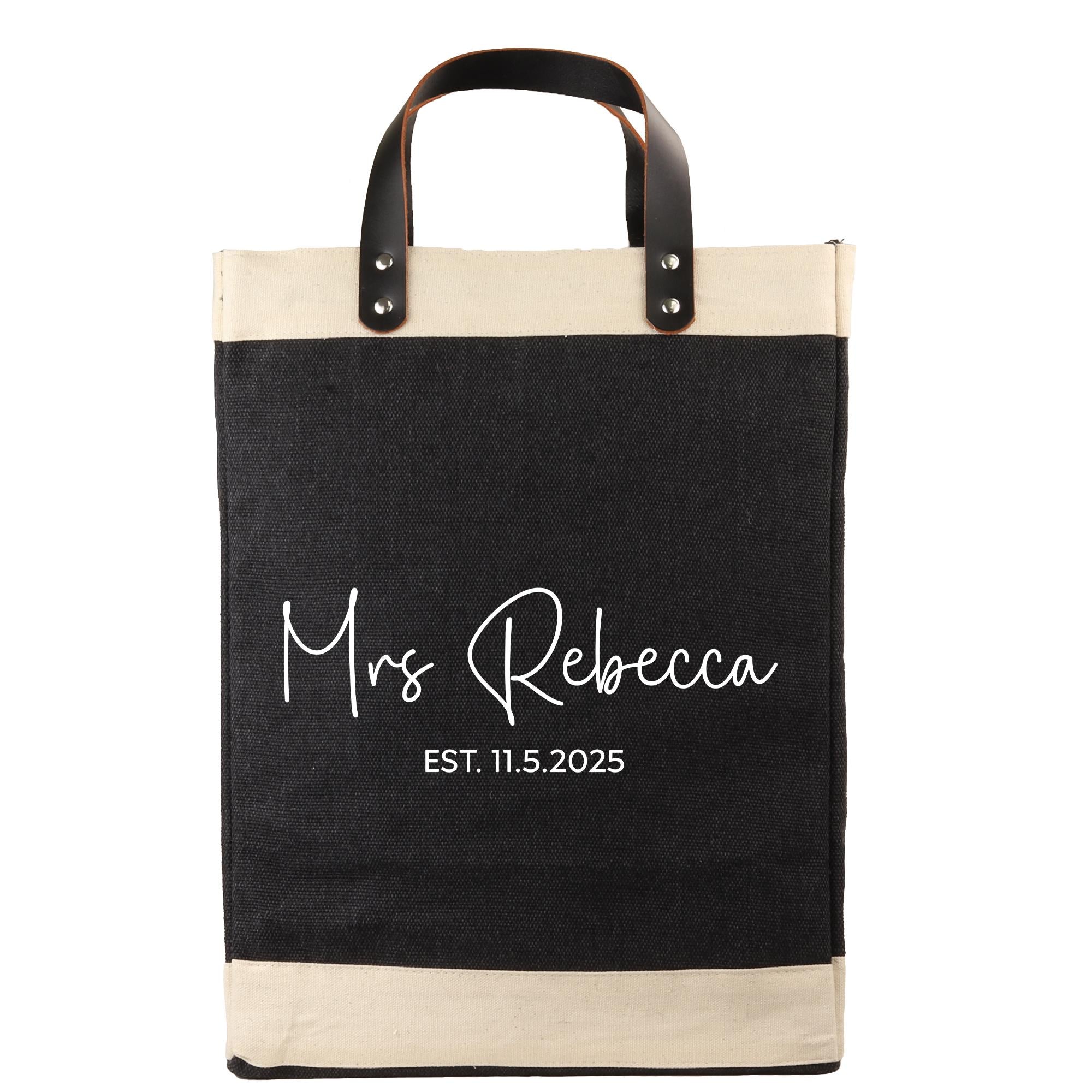 A black and beige tote bag with the text "Mrs Rebecca EST. 11.5.2025" printed on it.