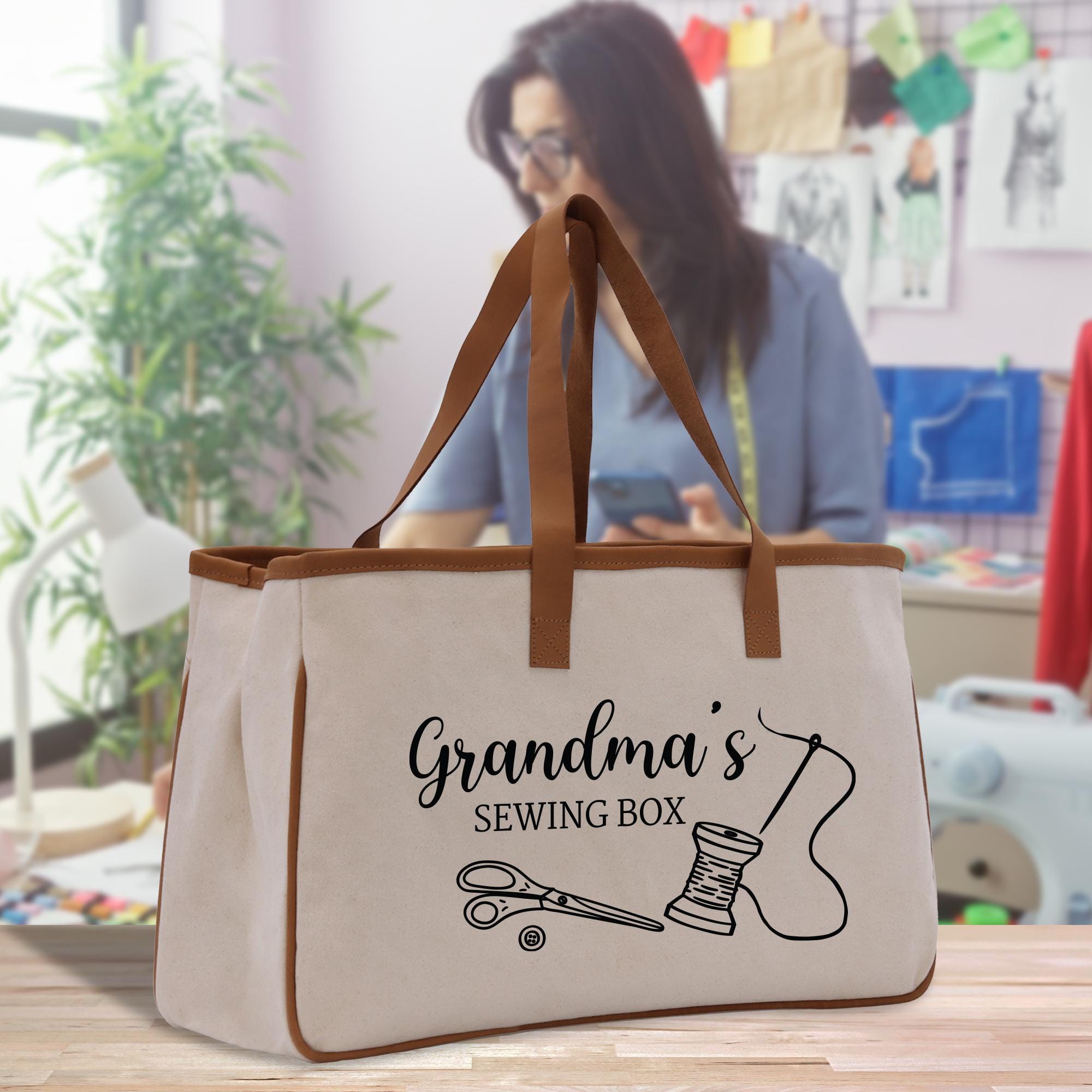 A beige tote bag with the text &quot;Grandma&#39;s Sewing Box&quot; printed on it, featuring a sewing kit illustration.