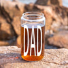 A glass jar filled with a brown liquid, with the word "DAD" printed on it in white letters.