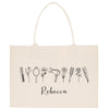 A beige canvas tote bag with a hand-drawn line art design of various hair styling tools and accessories, including a hair dryer, straightener, brush, and scissors, along with the name "Recca" written below.