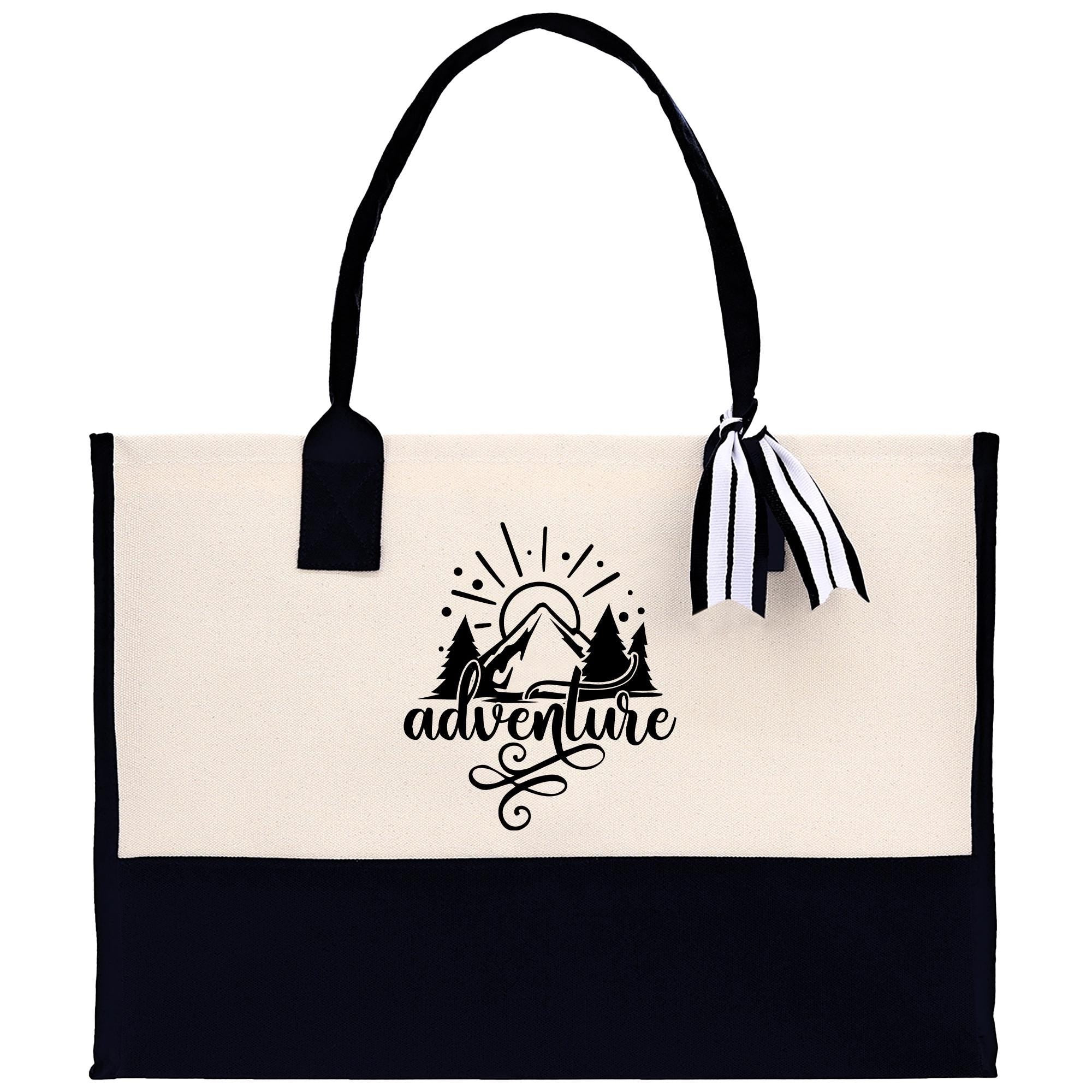 A beige tote bag with a black and white graphic design on the front, featuring a sun and mountain silhouette, along with the word "adventure" written below.
