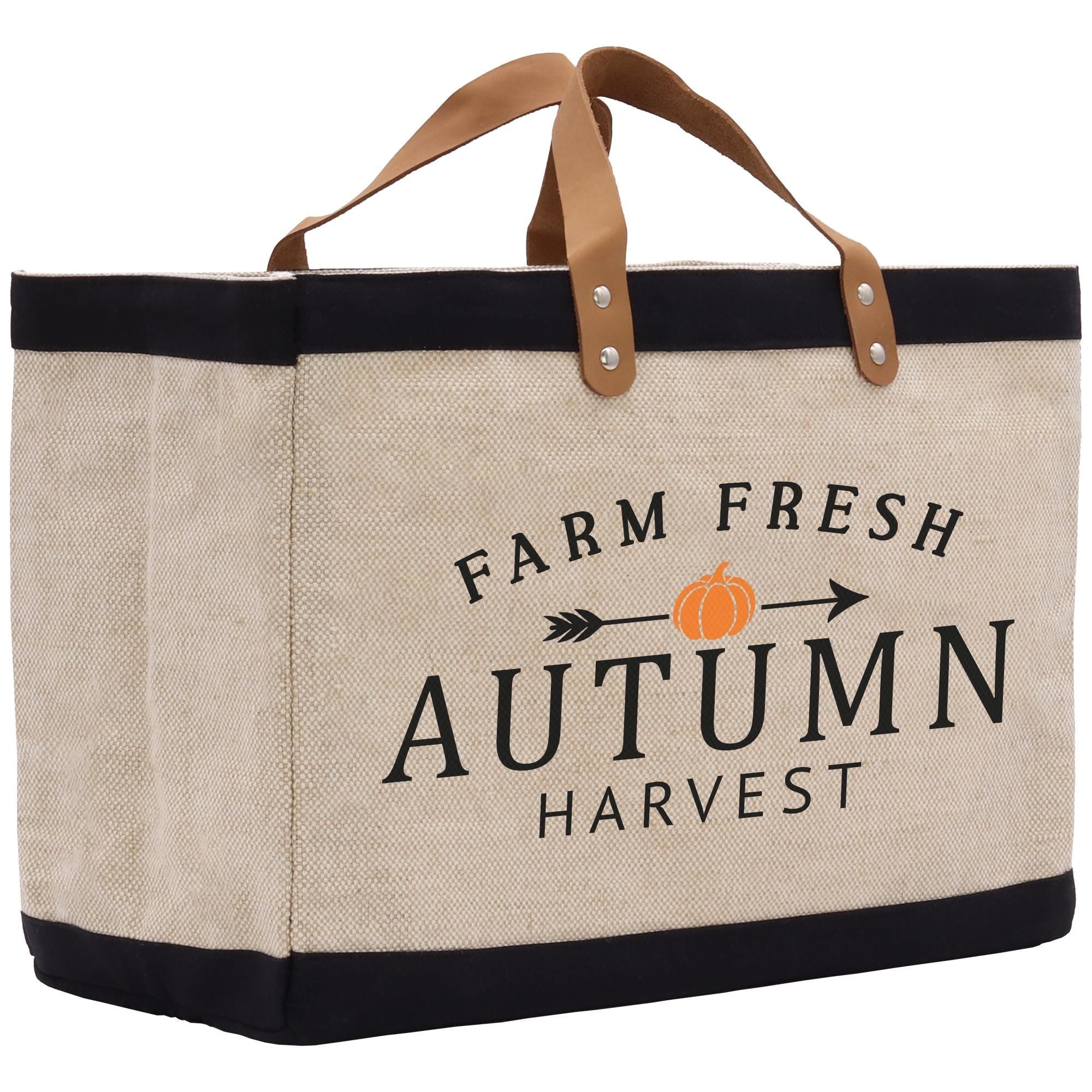 A beige tote bag with black trim and a brown leather handle, featuring the text &quot;FARM FRESH AUTUMN HARVEST&quot; printed on it.