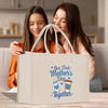 two women sitting on a couch looking at a bag