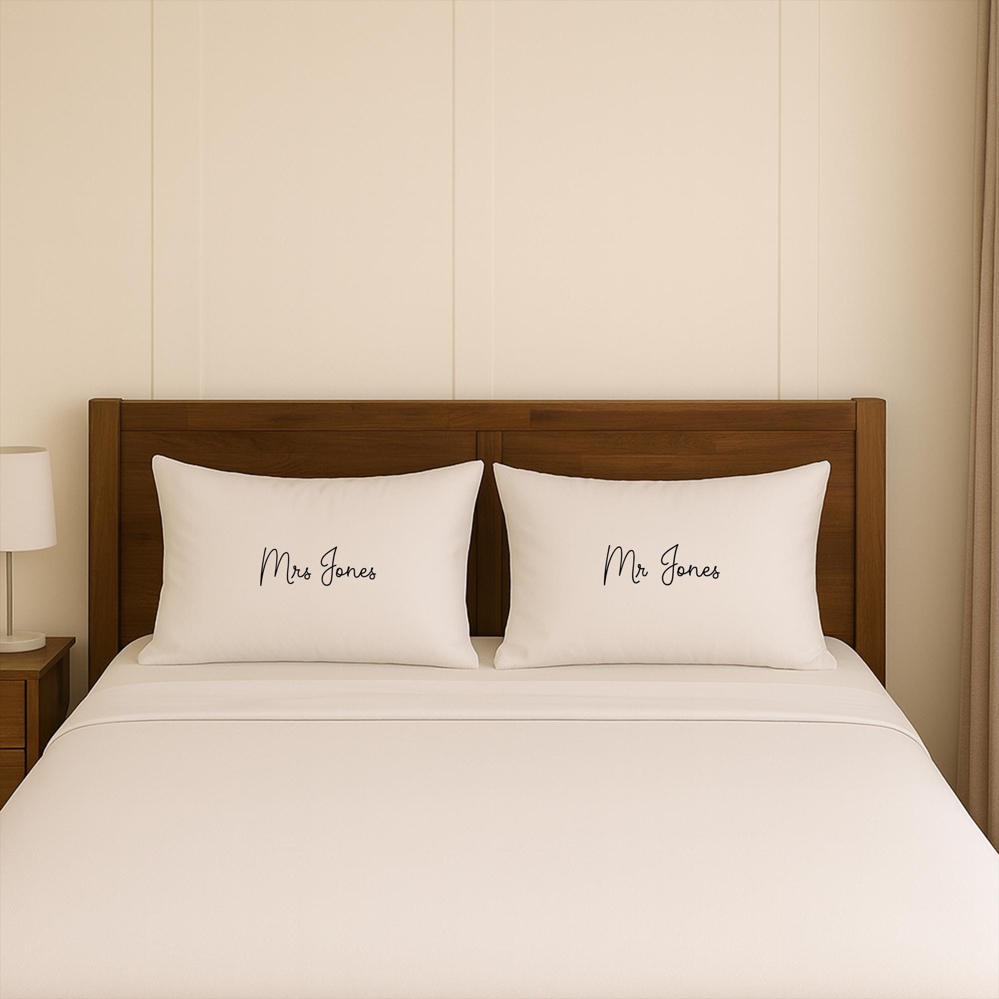 A neatly made bed with two white pillows, each with the name &quot;Mrs Jones&quot; written on it.