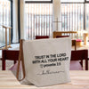 A white canvas tote bag with black text and a leather strap, placed on a wooden surface.