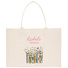 A beige tote bag with a printed design of colorful books and flowers.