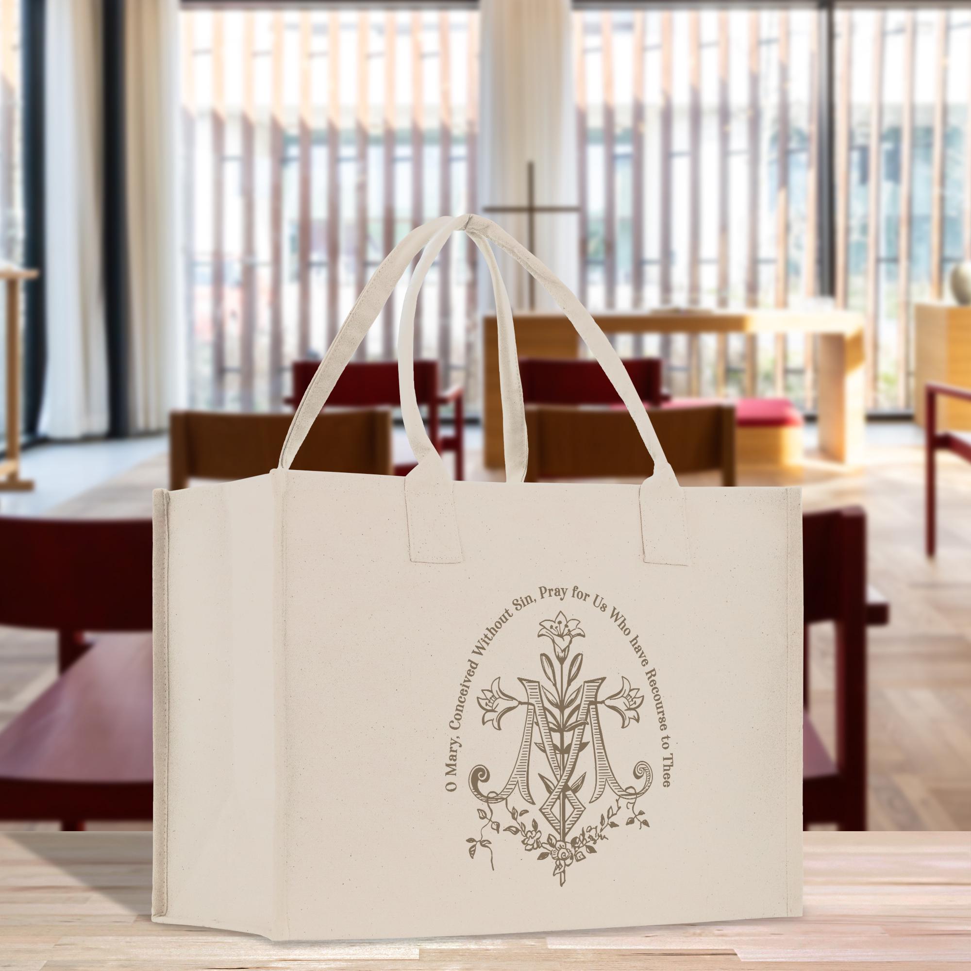 A white tote bag with a circular emblem featuring a cross and floral design, placed on a wooden surface.