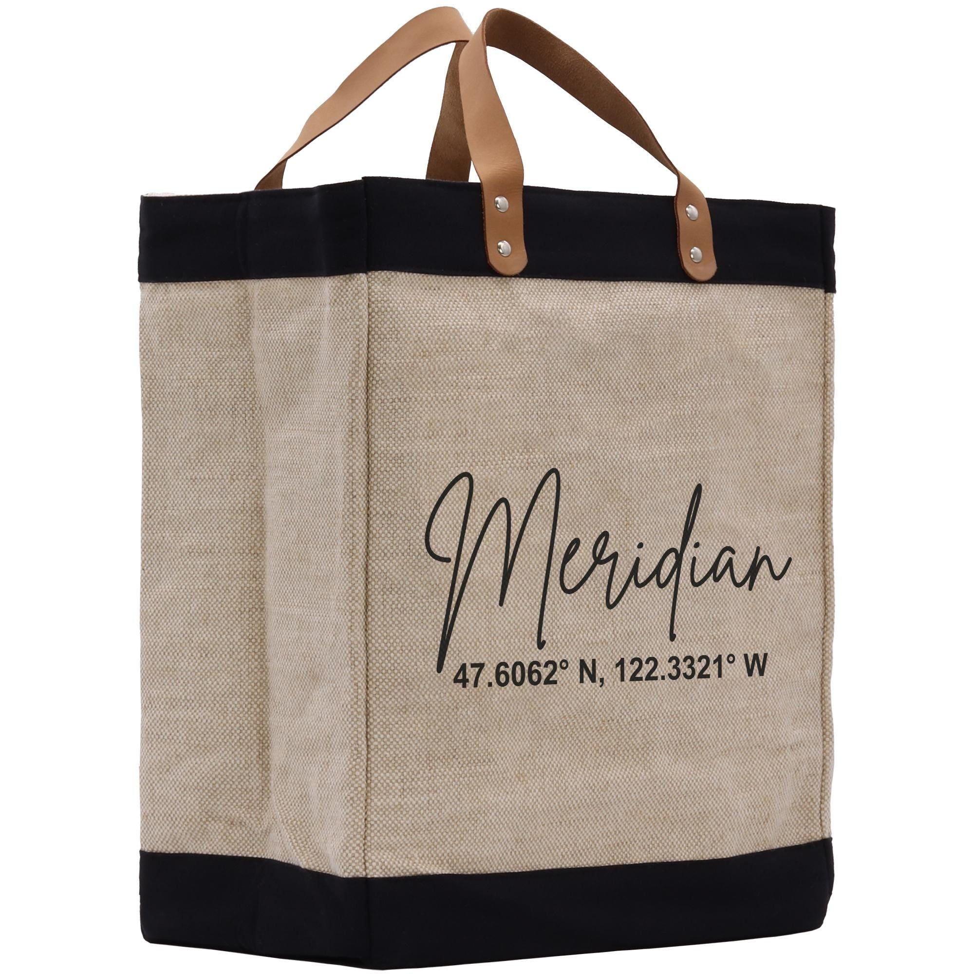 A beige tote bag with black trim and leather handles, featuring a personalized text and location printed on it.