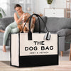 a woman sitting on a couch with a dog in a bag
