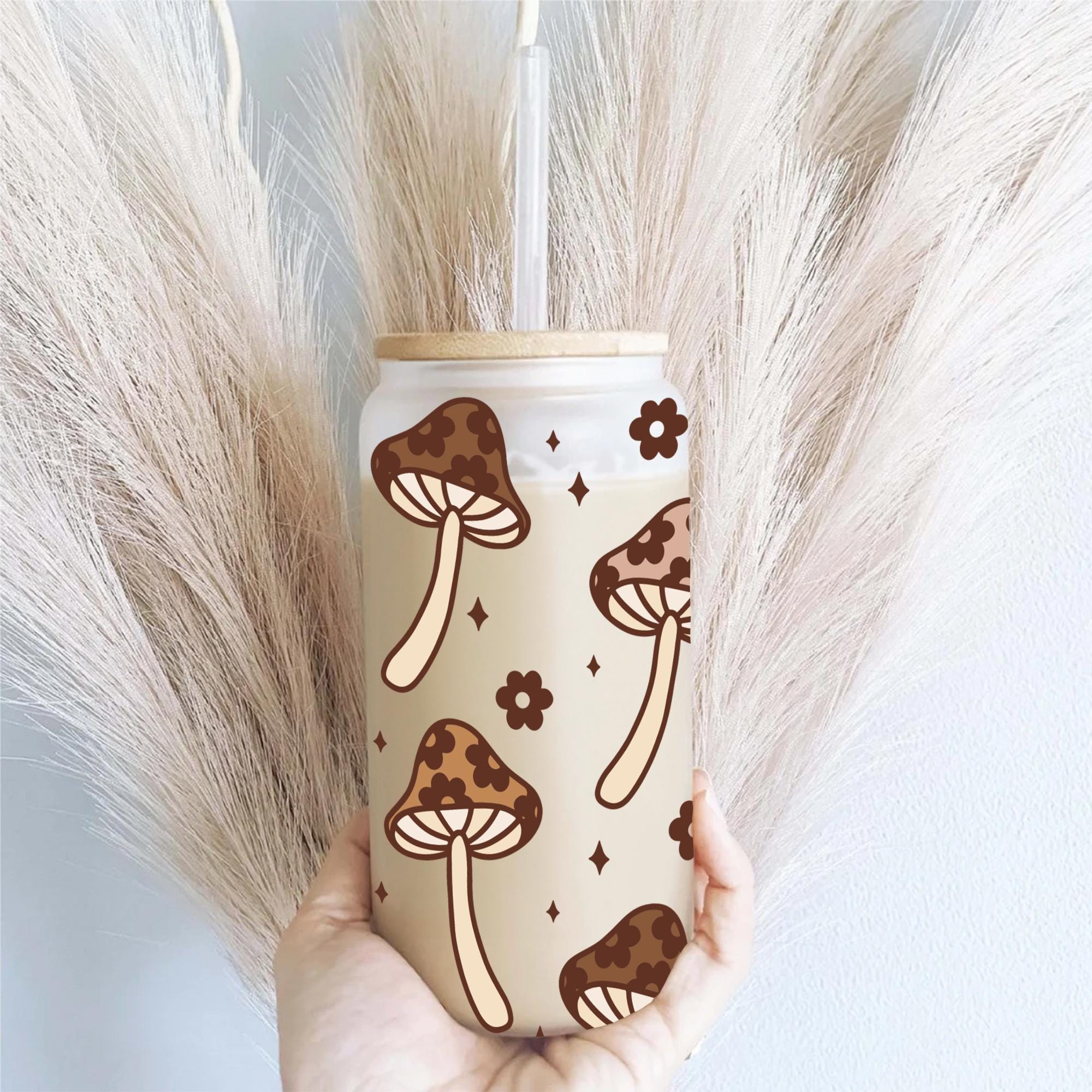 a person holding a cup with a pattern of mushrooms on it