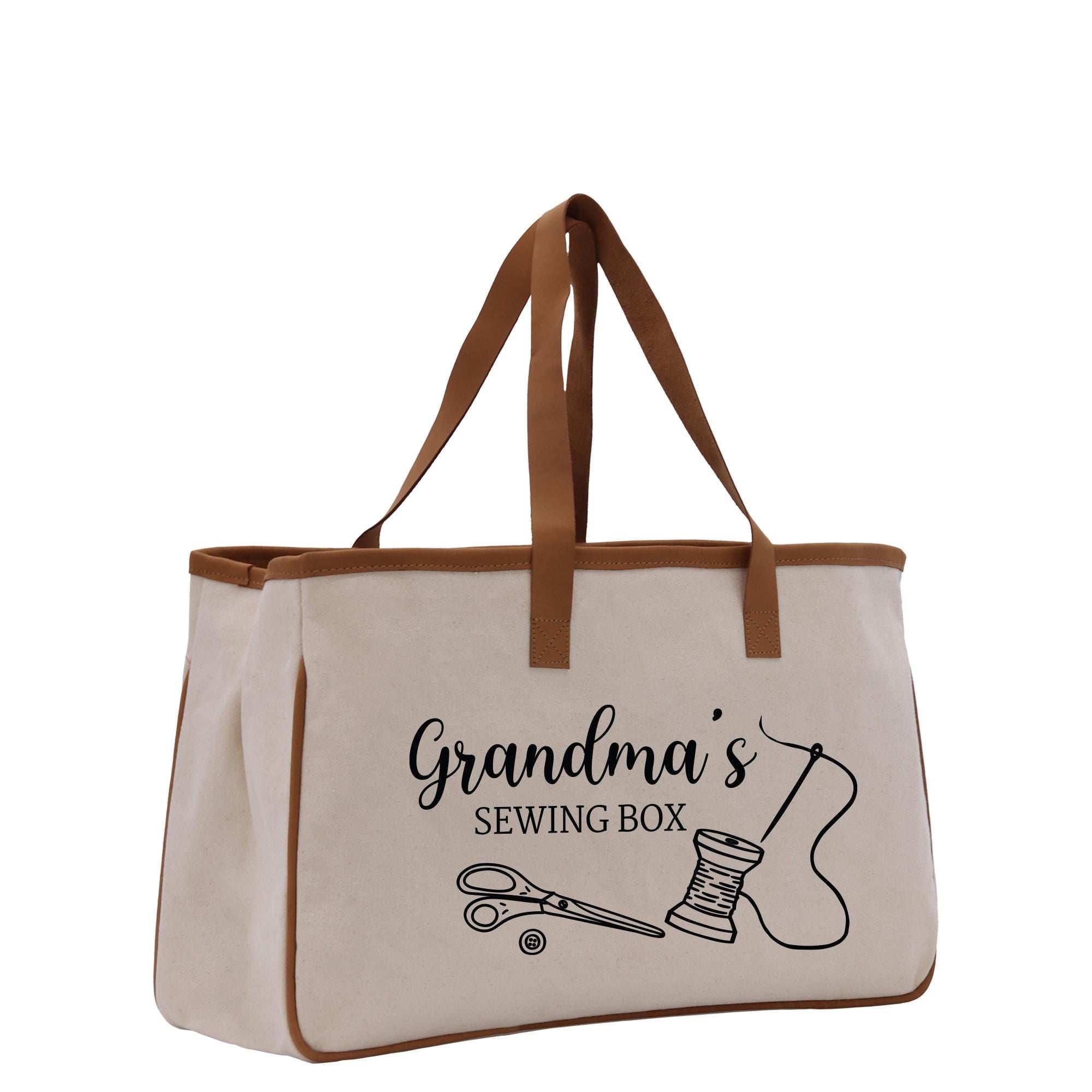 A beige canvas tote bag with the text &quot;Grandma&#39;s Sewing Box&quot; printed on it, along with illustrations of sewing-related items such as scissors and a spool of thread.