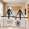 Two beige tote bags with black handles and straps, featuring text and logos related to real estate.