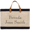 A beige tote bag with black trim and leather handles, featuring personalized text that says "Benda Joan Smith".