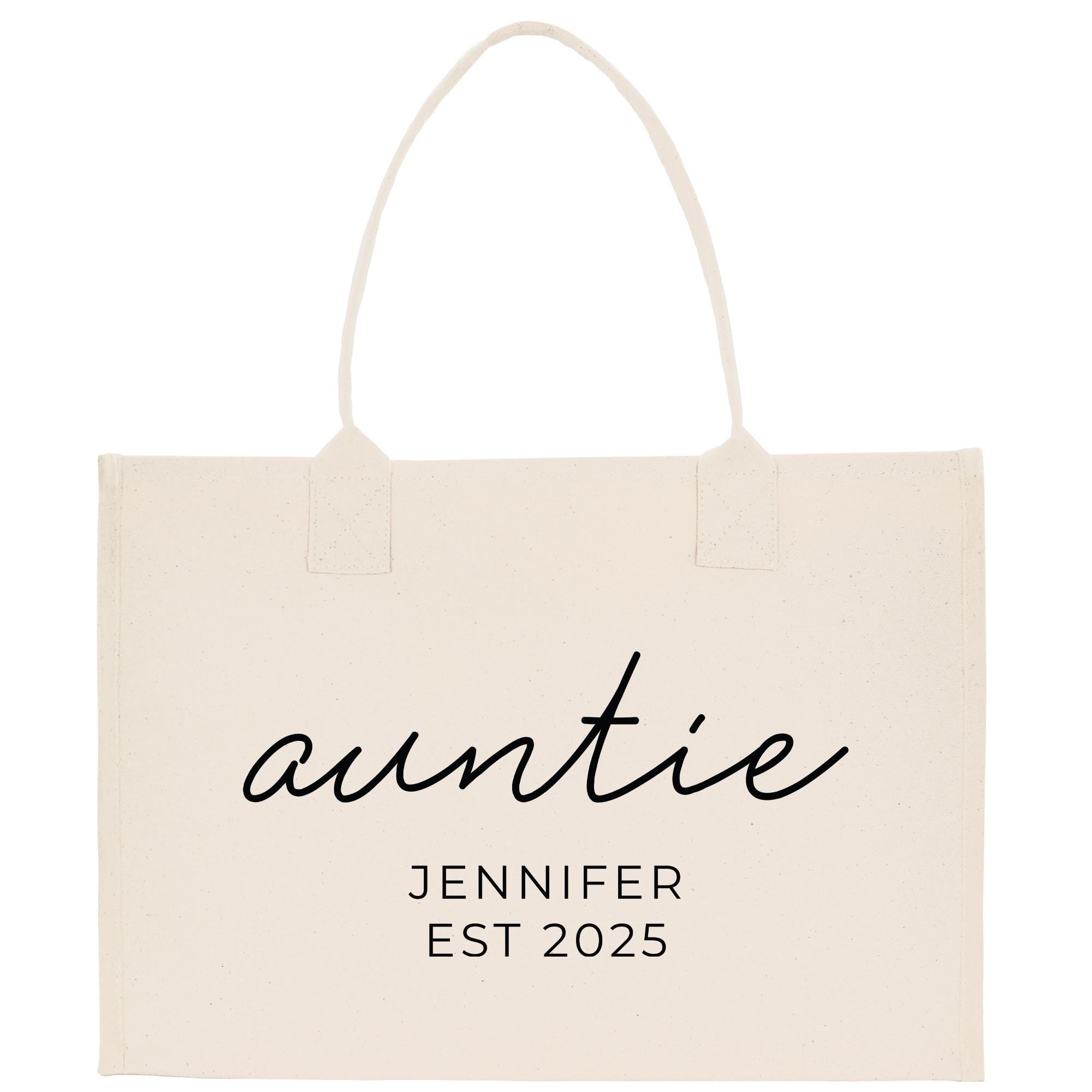 A beige canvas tote bag with the text &quot;auntie&quot; and &quot;JENIFER EST 2025&quot; printed on it.