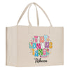 A beige canvas tote bag with a colorful graphic design featuring the text "Tiny humans timer" and the name "Recca" printed on it.