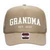 A tan-colored trucker hat with the text "GRANDMA EST. 2025" printed on it.