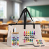 A beige tote bag with a handle and a glass jar with a straw, both featuring colorful crayon designs, are displayed on a wooden surface.