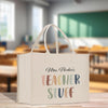 A white tote bag with text printed on it, placed on a wooden surface.