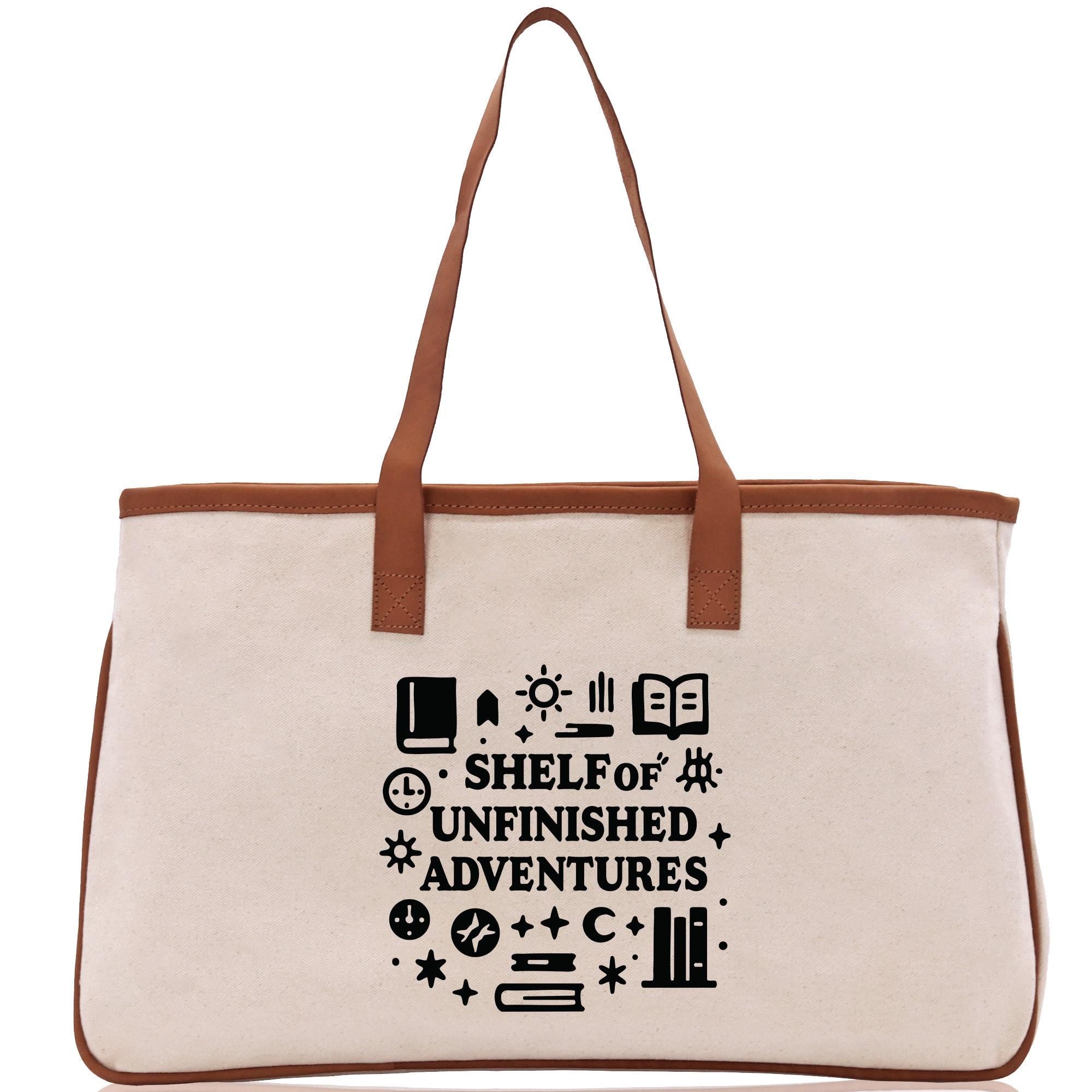 A beige canvas tote bag with a brown handle and a printed design on the front that says &quot;SHELF OF UNFINISHED ADVENTURES&quot;.