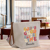 A beige tote bag with a colorful text design printed on it, sitting on a wooden surface.
