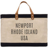 A beige tote bag with black trim and leather handles, featuring the text "NEWPORT RHODE ISLAND USA" printed on it.
