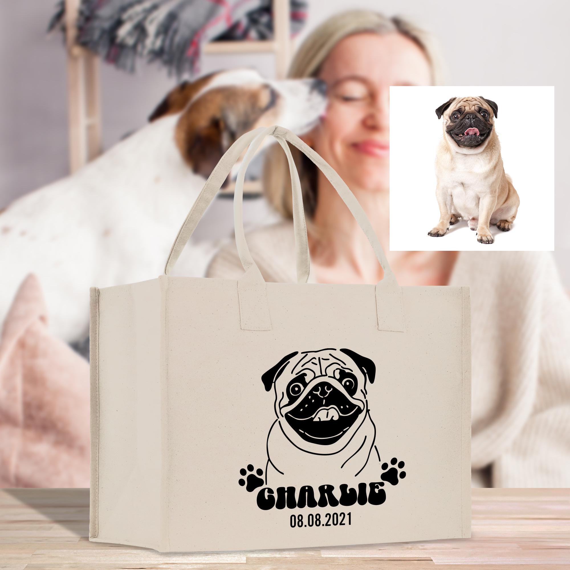 A beige tote bag with a black and white illustration of a pug dog and the text &quot;CHARLIE&quot; printed on it, along with the date &quot;08.08.2021&quot;.