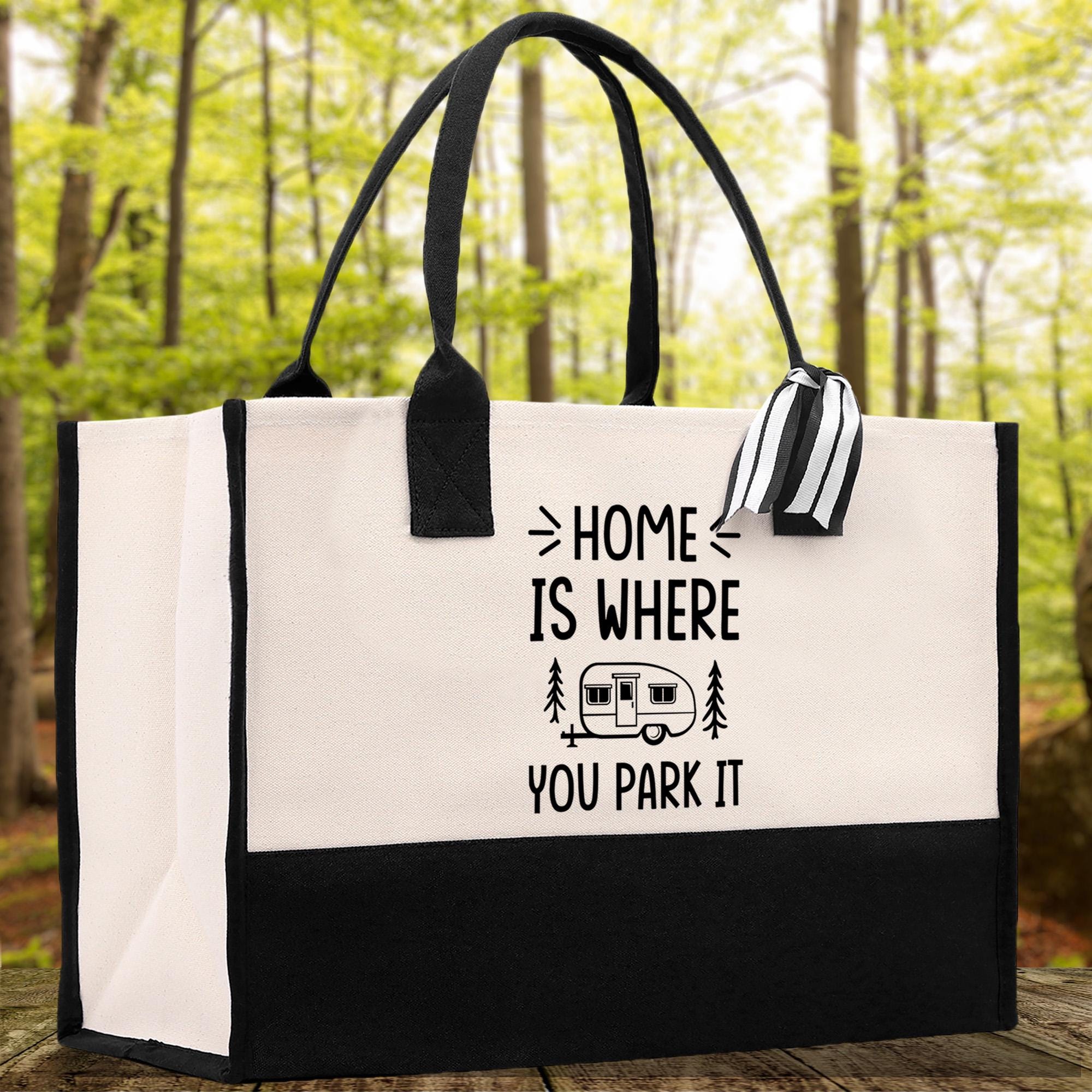 A black and white tote bag with the text "HOME IS WHERE YOU PARK IT" printed on it, along with a graphic of a camper van.