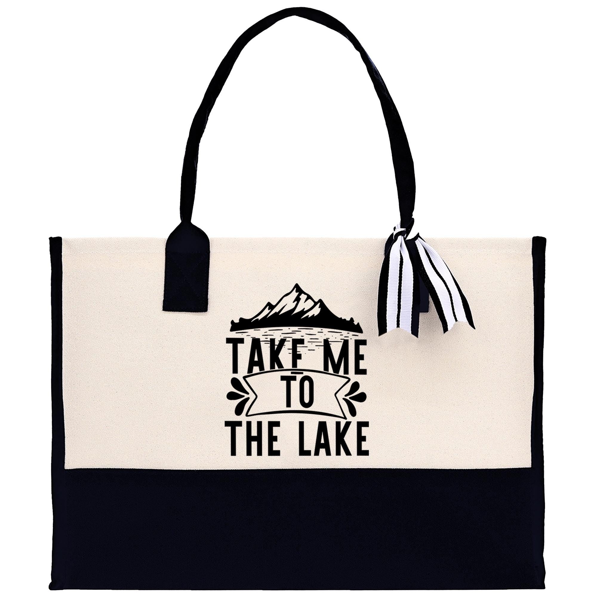 A black and white tote bag with the text "TAKE ME TO THE LAKE" printed on it.