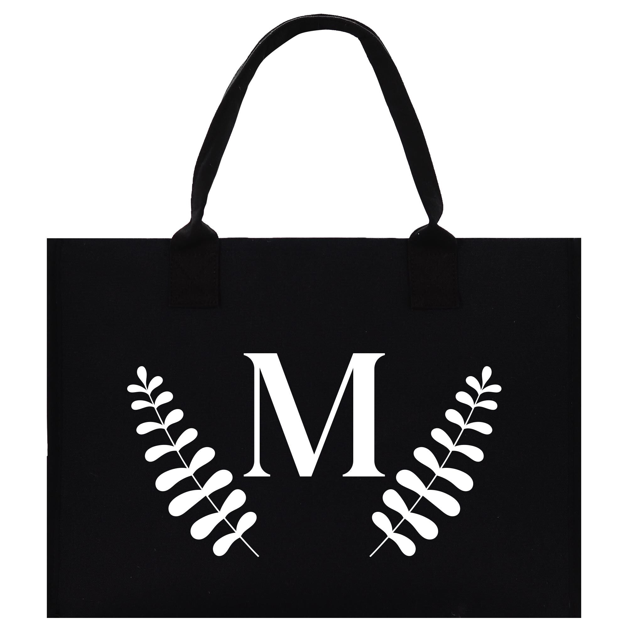 A black paper bag with a white monogrammed letter &quot;M&quot; and leaf-like designs on the front.