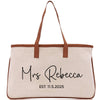 A beige canvas tote bag with brown straps and the text "Mrs Rebecca EST. 11.5.2025" printed on it.