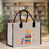 A beige tote bag with a printed design of a stack of colorful books and a cat on top, placed on a wooden surface.