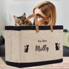 a woman is holding a canvas bag with a cat in it