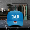 A blue baseball cap with the text "DAD EST. 2025" printed on it, placed on a marble countertop.