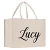 A beige canvas tote bag with the name "Lucy" printed on it in a cursive font.