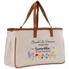 A beige tote bag with a floral design and text printed on it.