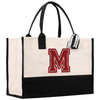 A large tote bag with a monogrammed letter "M" on it, featuring a black and white striped handle.