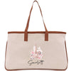 A beige canvas tote bag with a brown leather strap and a printed image of the Eiffel Tower on it.