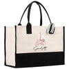 A beige tote bag with a black handle and a black and white striped ribbon attached to it. The bag has a printed image of the Eiffel Tower on it, and the name "Sarlett" is written below the image.