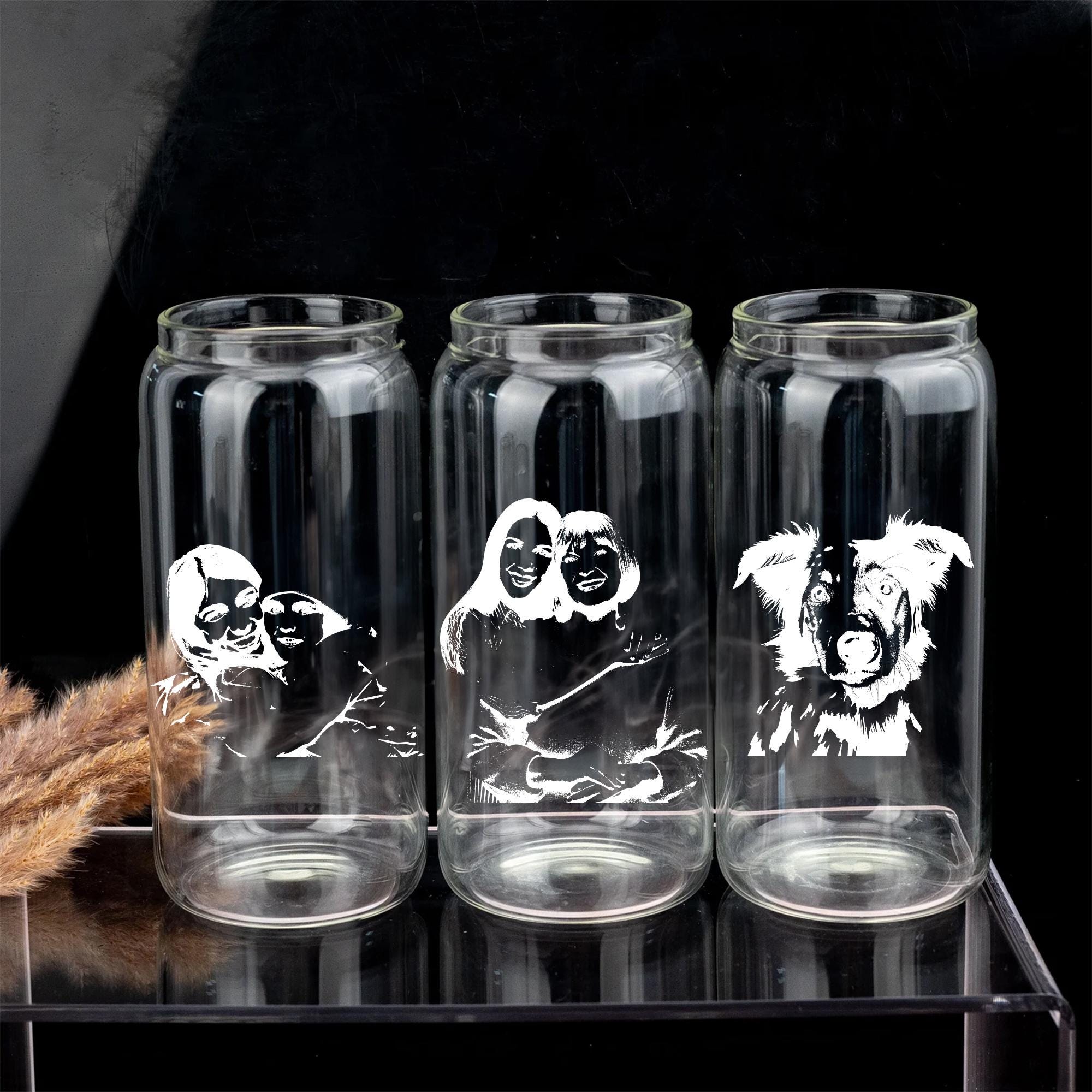 Three clear glass tumblers with black and white illustrations of people and dogs printed on them.
