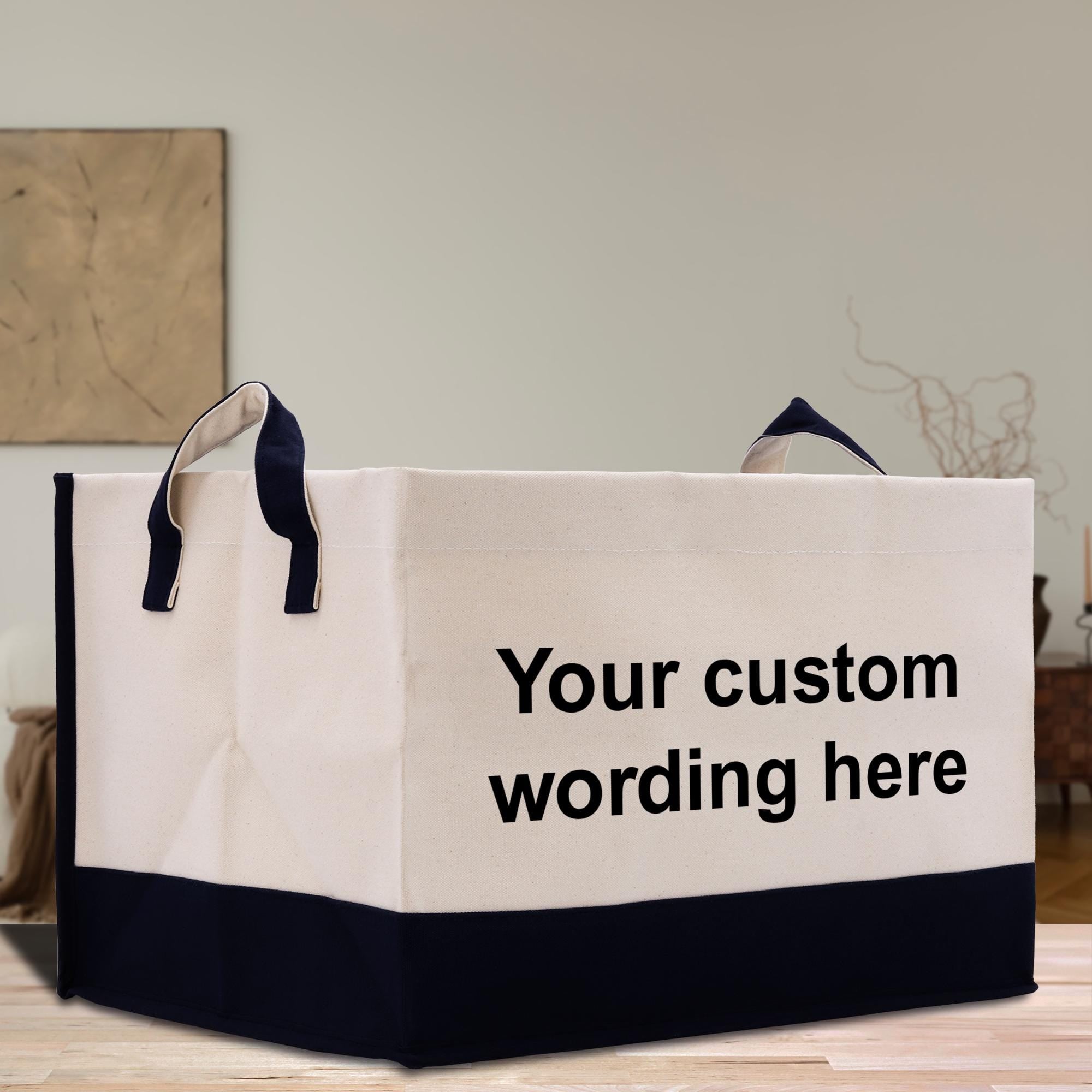 A white and black tote bag with the text &quot;Your custom wording here&quot; printed on it, placed on a wooden surface.